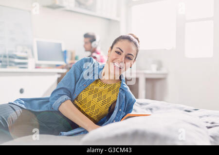 Portrait smiling young adult woman reading on bed Stock Photo