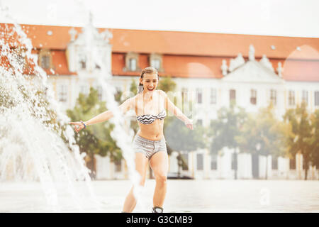 Young woman travels with inline skates through a fountain Stock Photo