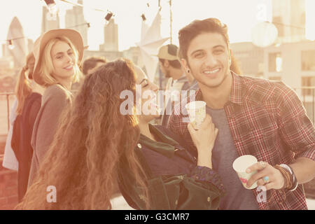 Young adult friends drinking and laughing at rooftop party Stock Photo