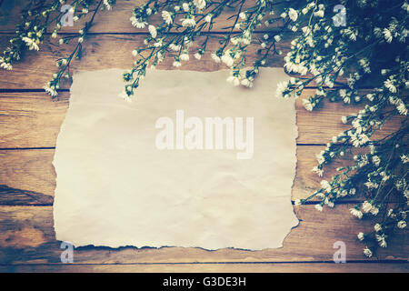 Flowers and old paper on wood texture background with copyspace. Vintage style. Stock Photo