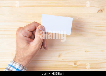 Top view of businessman holding blank business card on office desk, mock up copy space for graphic design or text placement. Stock Photo