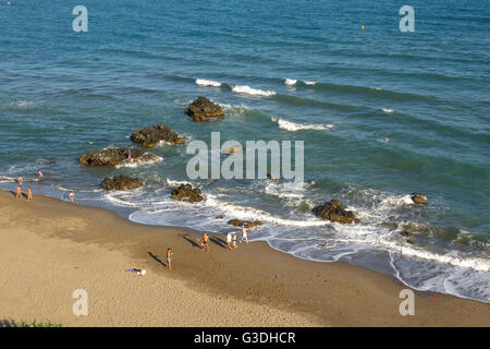Some people enjoying late sun on empty beach during low season, Costa del Sol, Spain. Stock Photo