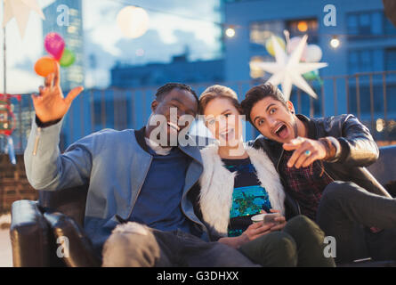 Portrait enthusiastic friends enjoying rooftop party Stock Photo