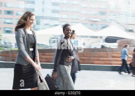 Portrait smiling corporate businesswoman walking outdoors Stock Photo