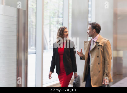 Corporate businessman explaining to businesswoman in office lobby Stock Photo