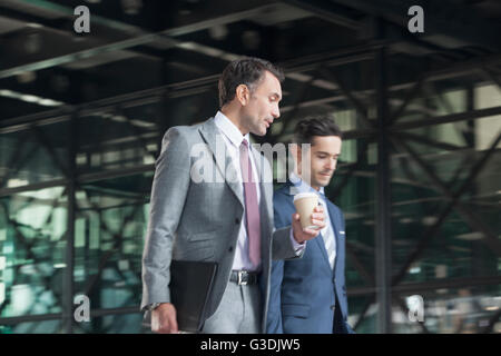 Corporate businessmen with coffee talking and walking Stock Photo