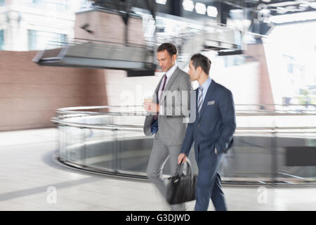 Corporate businessmen with coffee walking and talking Stock Photo