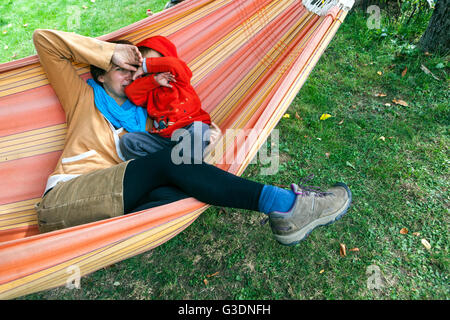 Mother playing with her son in a hammock in the garden Stock Photo