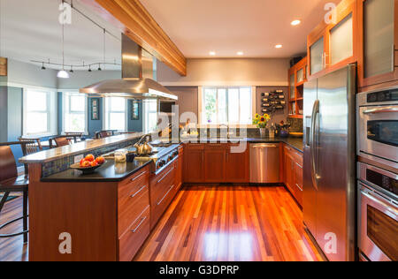 Spacious, contemporary upscale home kitchen interior with wood cabinets & floors, accent lighting & stainless steel appliances Stock Photo