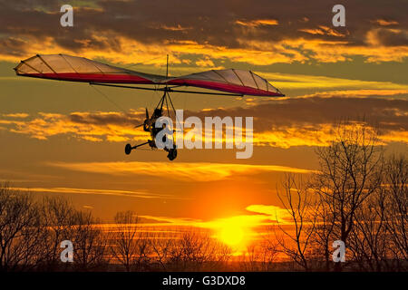 The motorized hang glider fly in the sunset Stock Photo