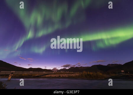 The aurora borealis dances in the sky over the Dietrich River and the Trans Alaska Pipeline in the Brooks Range north of Wiseman, Alaska. Stock Photo
