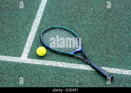 Tennis racket and tennis ball on a hard tennis court Stock Photo