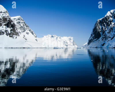 Breathtaking scenery with snow capped mountains reflected in the clear blue waters of the Lemaire Channel, Antarctica Stock Photo