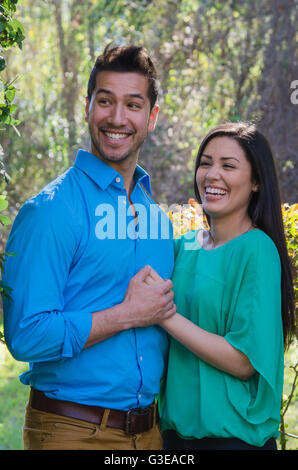 Young Hispanic couple holding hands laughing outside Stock Photo