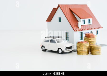 Car and house model with stack of coins isolated on white background Stock Photo