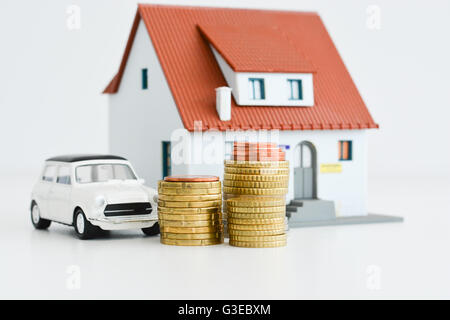 Car and house model with stack of coins isolated on white background Stock Photo