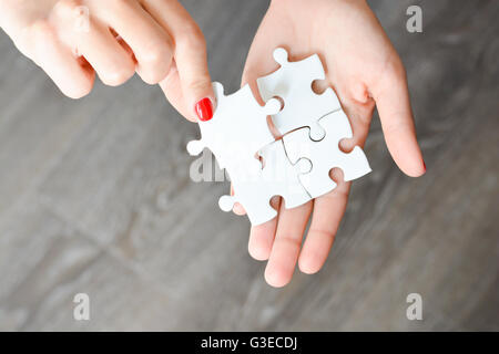 Woman hand fitting the right piece of puzzle suggesting business  networking concept Stock Photo