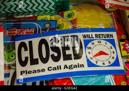 A store closed sign with a time of return clock on it. Stock Photo