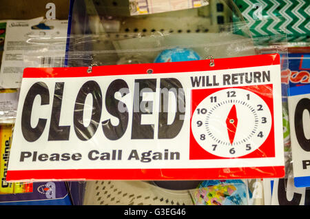 A store closed sign with a time of return clock on it. Stock Photo