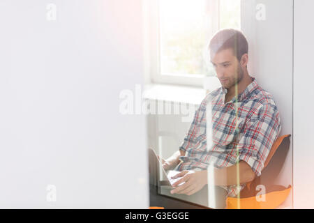 Casual businessman using laptop in office window Stock Photo