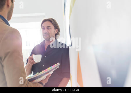 Creative businessmen drinking coffee and talking in office Stock Photo