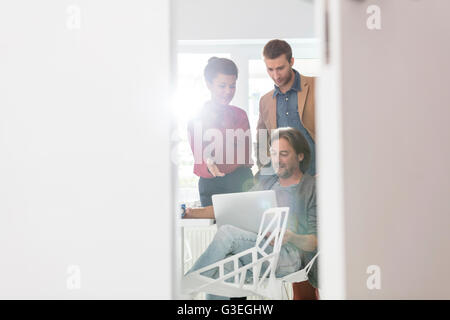 Creative business people sharing laptop in office meeting Stock Photo