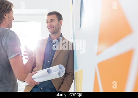 Architects with blueprints talking in office Stock Photo