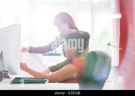 Female architects discussing blueprints at desk and office Stock Photo