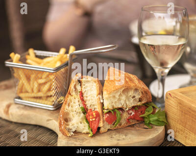 Vegetarian Italian Style Red Pepper Ciabatta Bread Sandwich With Glass  White Wine On Wooden Serving Board with Chips Or Fries Stock Photo