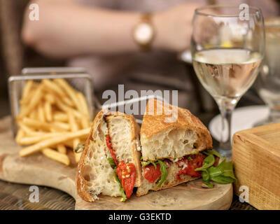 Vegetarian Italian Style Red Pepper Ciabatta Bread Sandwich With Glass  White Wine On Wooden Serving Board with Chips Or Fries Stock Photo