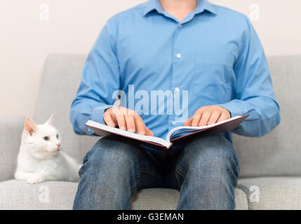 Blind man reading braille book on the couch. Stock Photo