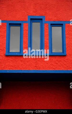 Bright red wall with dark blue window frames in an Art Deco building Kinsale, County Cork Ireland Stock Photo