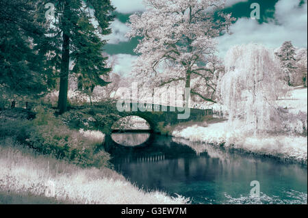 Stunning infra red landscape image of old bridge over river in countryside Stock Photo