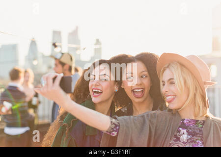 Enthusiastic young women taking selfie at rooftop party Stock Photo