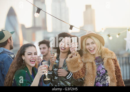 Portrait enthusiastic young women drinking champagne at rooftop party Stock Photo