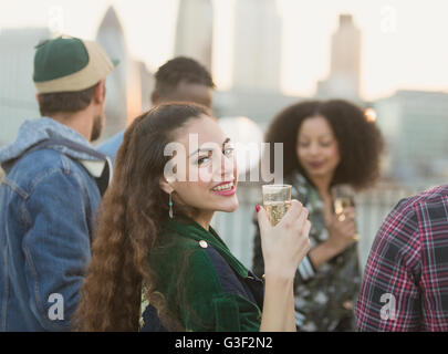 Portrait smiling young woman drinking champagne at rooftop party