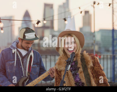 Musicians playing guitar and singing at rooftop party Stock Photo
