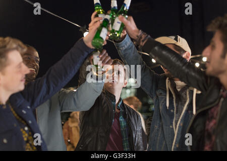 Young men toasting beer bottles at party Stock Photo