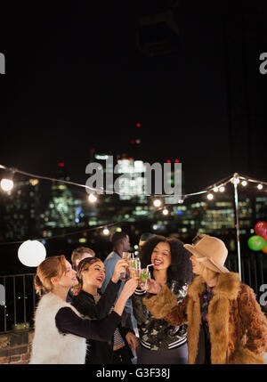 Young women toasting cocktails at nighttime rooftop party Stock Photo