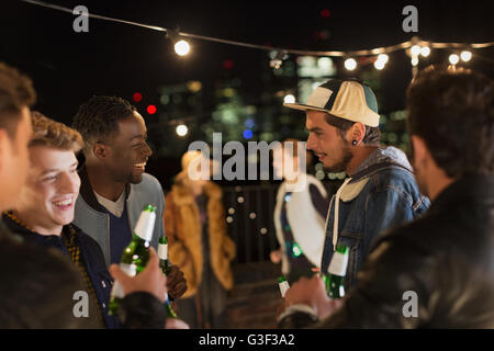 Young friends talking and drinking at rooftop party Stock Photo