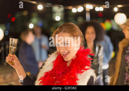 Portrait enthusiastic young woman drinking champagne at rooftop party Stock Photo