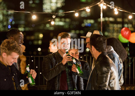 Young men drinking beer at rooftop party Stock Photo