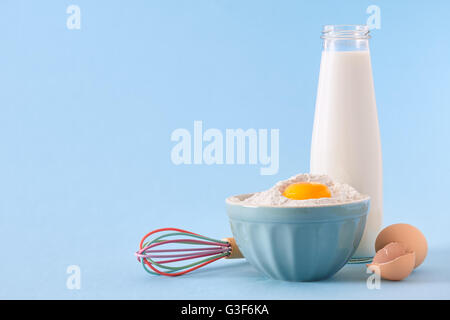 Milk bottle, eggs and bowl with flour Stock Photo