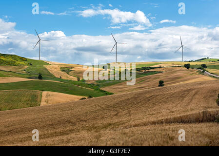 Row of wind turbines in a wind farm on the hilltops viewed across rolling agricultural land in a concept of alternative power an Stock Photo