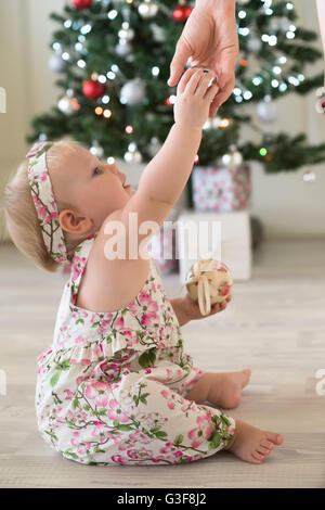 Baby girl in front of Christmas tree with gifts and decorations Stock Photo