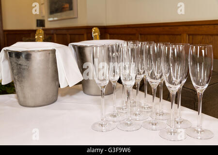 Row of champagne flutes and two bottles in ice buckets ready for pouring toast. Stock Photo