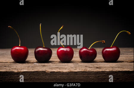 Five delicious big cherries on a rustic wooden table Stock Photo