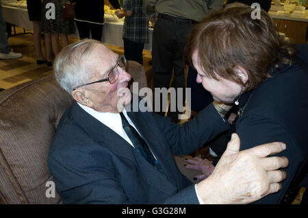 Woman age 75 greets her 95 year old cousin at his birthday party. Redwood Falls Minnesota MN USA Stock Photo