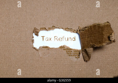 The word tax refund appearing behind torn paper. Stock Photo