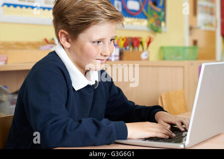 Male Elementary School Pupil Using Laptop In Computer Class Stock Photo